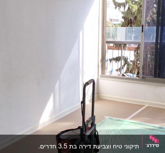 חדר עם קירות לבנים, ציוד לצביעה על הרצפה